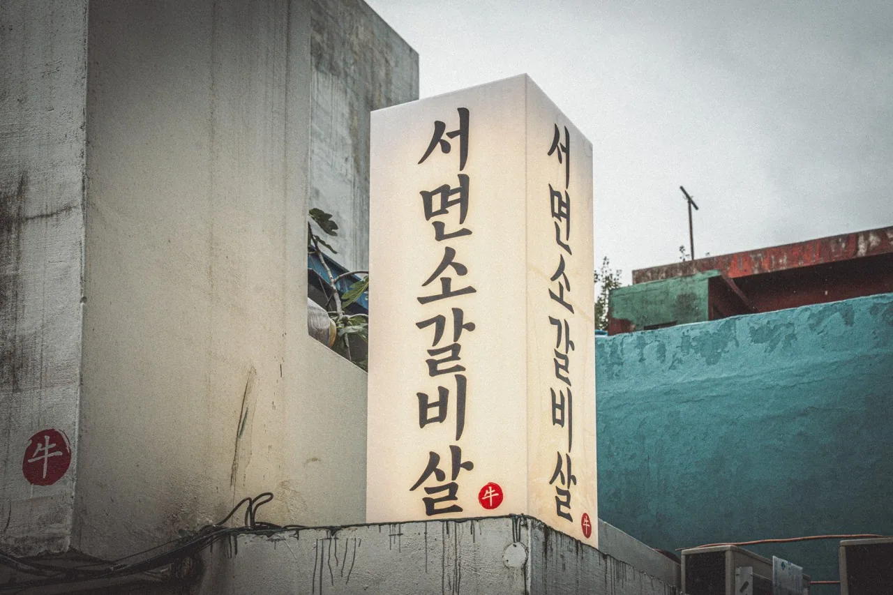 붓글씨로 세로 조판된 서면소갈비살 조명간판과 붉은 낙관